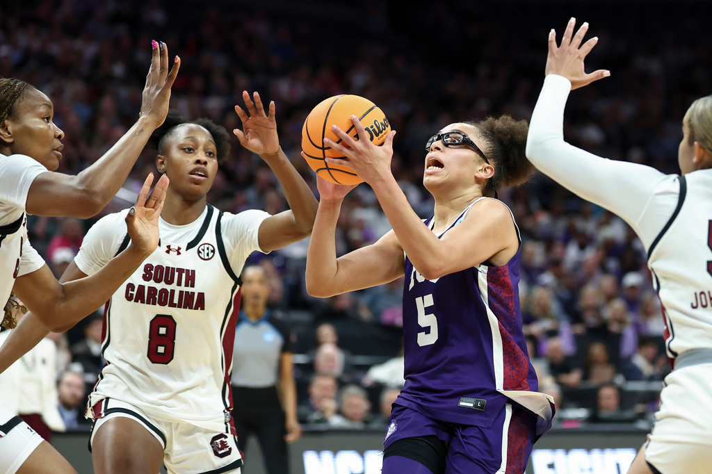 TCU guard Olivia Miles (5) drives to the basket with South Carolina forwards Joyce Edwards (8) and Maryam Dauda, left, defending during the first half in the Elite Eight of the NCAA college basketball tournament Monday, March 30, 2026, in Sacramento, Calif. (AP Photo/Sara Nevis)