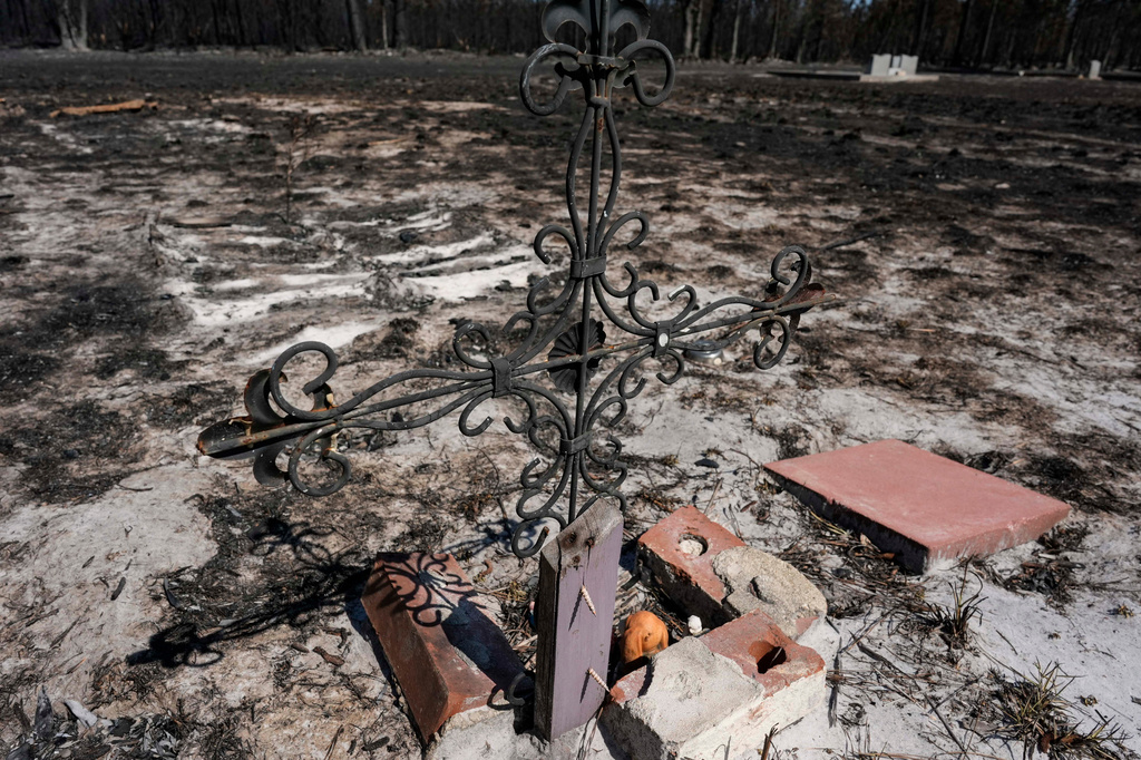 A grave marker in a cemetery is burned near destroyed homes as the Brantley Highway 82 fire burns, Thursday, April 23, 2026, near Nahunta, Ga. (AP Photo/Mike Stewart)