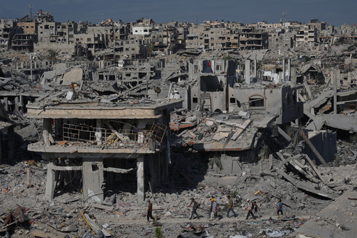Displaced Palestinians walk through an area surrounded by destroyed buildings in Khan Younis, in the southern Gaza Strip, Saturday, Oct. 11, 2025, after Israel and Hamas agreed to a pause in their war and the release of the remaining hostages. (AP Photo/Jehad Alshrafi) Displaced Palestinians walk through an area surrounded by destroyed buildings in Khan Younis, in the southern Gaza Strip, Saturday, Oct. 11, 2025, after Israel and Hamas agreed to a pause in their war and the release of the remaining hostages. (AP Photo/Jehad Alshrafi)
