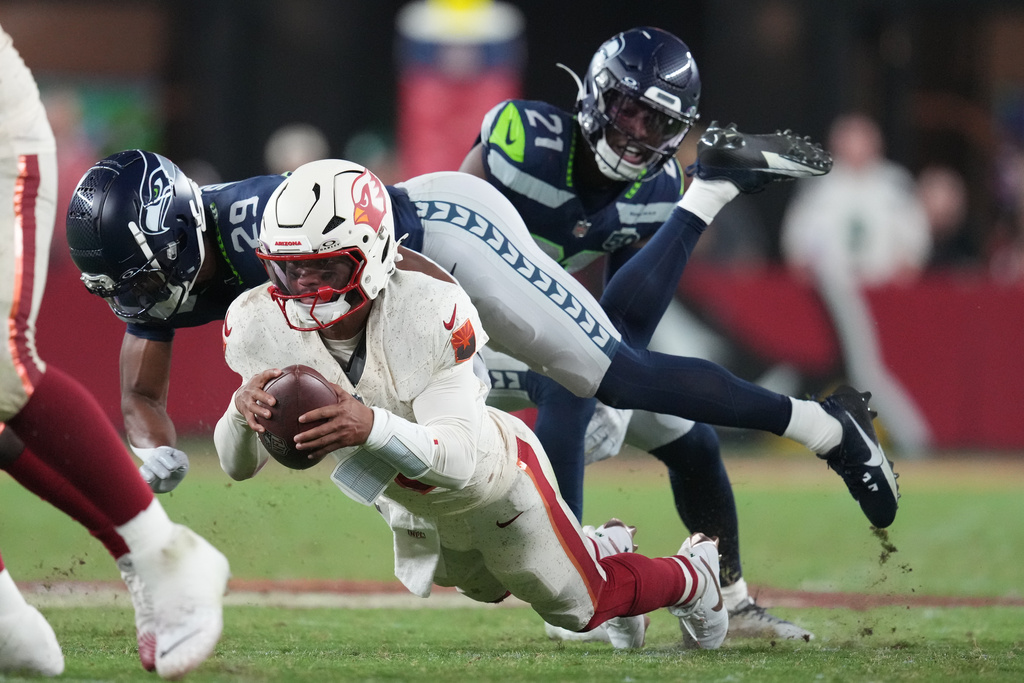 Arizona Cardinals quarterback Kyler Murray, front, is sacked by Seattle Seahawks cornerback Josh Jobe (29) and cornerback Devon Witherspoon (21) during the second half of an NFL football game Thursday, Sept. 25, 2025, in Glendale, Ariz. (AP Photo/Ross D. Franklin)