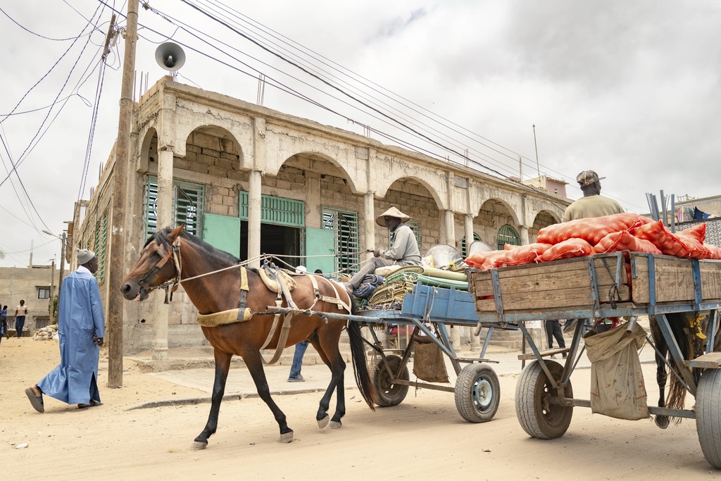 Merchants ride past the Great Mosque of Nietty Mbar in Thiaroye, a suburb of Dakar, Senegal, Friday, July 4, 2025.(AP Photo/Sylvain Cherkaoui)