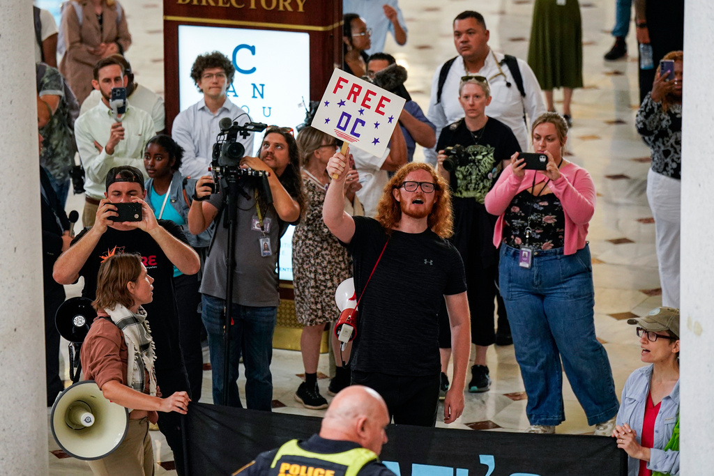 Demonstrators chant as White House Deputy Chief of Staff Stephen Miller, right, Defense Secretary Pete Hegseth and Vice President JD Vance, greet members of the National Guard, at Union Station in Washington, Wednesday, Aug. 20, 2025. (Al Drago/Pool via AP)