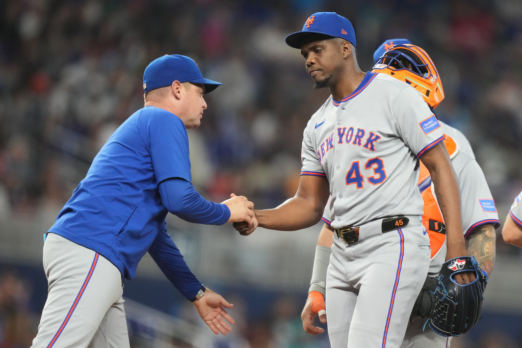 New York Mets relief pitcher Huascar Brazoban (43) hands the ball to manager Carlos Mendoza, left, after being relieved during the third inning of a baseball game against the Miami Marlins, Sunday, Sept. 28, 2025, in Miami. (AP Photo/Lynne Sladky)