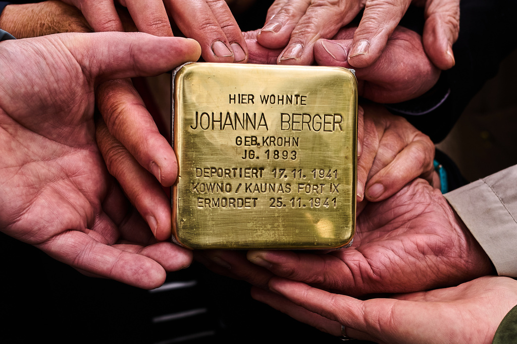 FILE - Relatives pose for a photograph holding a palm-sized brass Holocaust plaque in German reading, "Johanna Berger, born in 1893, lived here; deported on Nov. 17, 1941, murdered on Nov. 25, 1941 in Kowno/Kaunas Fort IX," by artist Gunter Demnig prior to the placing of the so called, "Stolperstein," or "Stumbling Blocks," in front of her former home in Berlin, Germany, May 6, 2026. (AP Photo/Markus Schreiber, File)