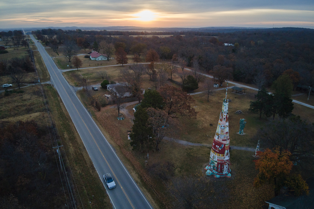 The sun rises over the horizon as a vehicle travels near a large Totem Pole at Ed Galloway's Totem Pole Park in Chelsea, Okla., Wednesday, Nov. 19, 2025. (AP Photo/Julio Cortez)