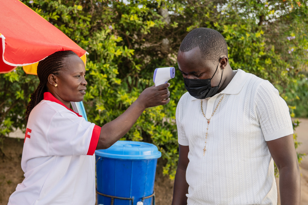 A health worker uses a thermometer to screen a man by the roadside in Bunia, Congo, Tuesday, May 19, 2026. (AP Photo/Moses Sawasawa)
