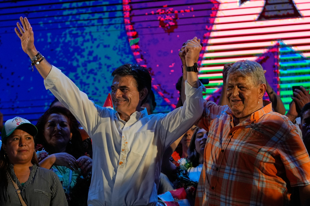 Former Bolivian President Jaime Paz, right, raises the arm of his son, presidential candidate Rodrigo Paz, during a closing campaign rally ahead of the upcoming runoff election in Tarija, Bolivia, Wednesday, Oct. 15, 2025.. (AP Photo/Juan Karita)