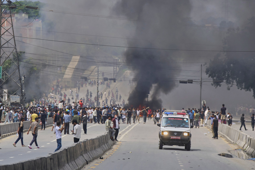 An ambulance drives past protesters burning tires to block streets during protests against social media ban and corruption in Kathmandu, Nepal, Tuesday, Sept. 9, 2025. (AP Photo/Niranjan Shrestha)