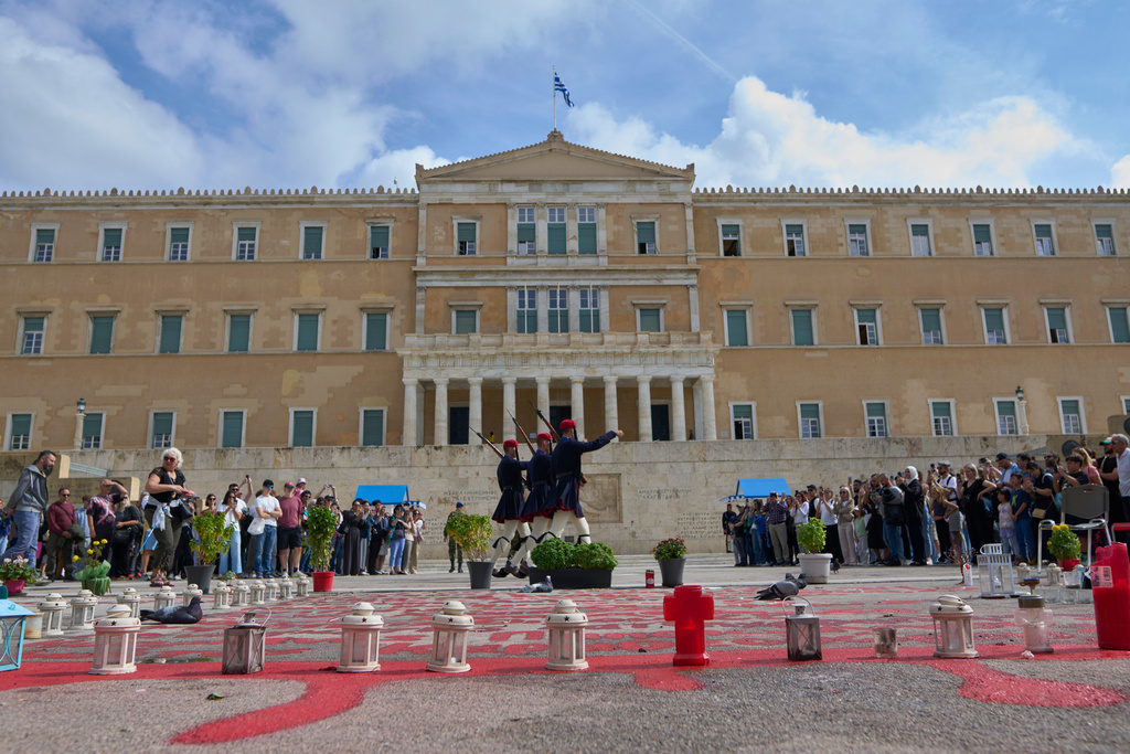Tourists watch the changing of the guard at the Tomb of the Unknown Soldier in front of the Greek parliament, in Athens, Tuesday, Oct. 21, 2025, as lawmakers debate regulations to protect the monument, recently the focus of protests by relatives of victims of Greece's deadliest train crash. (AP Photo/Petros Giannakouris)