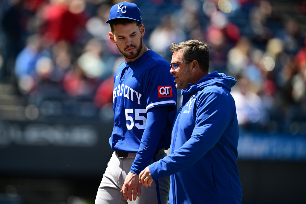Kansas City Royals starting pitcher Cole Ragans walks to the dugout with head athletic trainer Kyle Turner after being removed from the game after being hit by a line drive in the left hand by Cleveland Guardians' Jose Ramirez during the first inning of a baseball game, Wednesday, April 8, 2026, in Cleveland. (AP Photo/David Dermer)