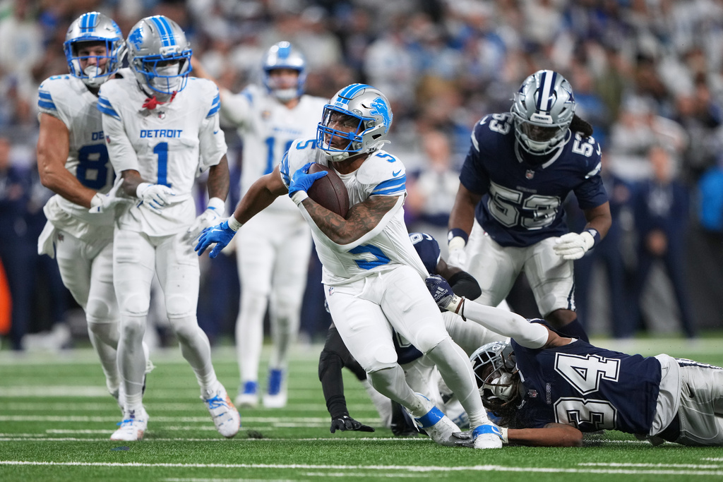 Detroit Lions running back David Montgomery (5) runs for a touchdown while Dallas Cowboys running back Malik Davis (34) tries to stop him during the first half of an NFL football game Thursday, Dec. 4, 2025, in Detroit. (AP Photo/Ryan Sun)