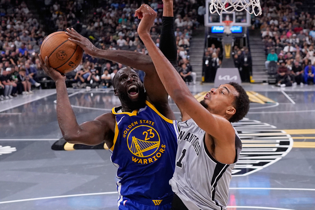 Golden State Warriors forward Draymond Green (23) drives to the basket against San Antonio Spurs forward Victor Wembanyama (1) during the second half of an NBA Cup basketball game in San Antonio, Friday, Nov. 14, 2025. (AP Photo/Eric Gay)