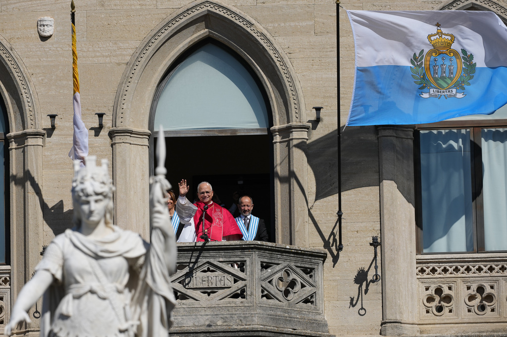 Pope Leo XIV, center, flanked by Captains Regent Alice Mina, left, and Vladimiro Selva, waves to faithful from the balcony of Palazzo Pubblico (City Hall) during his visit to San Marino, Saturday, Aug. 22, 2026. (AP Photo/Andrew Medichini)