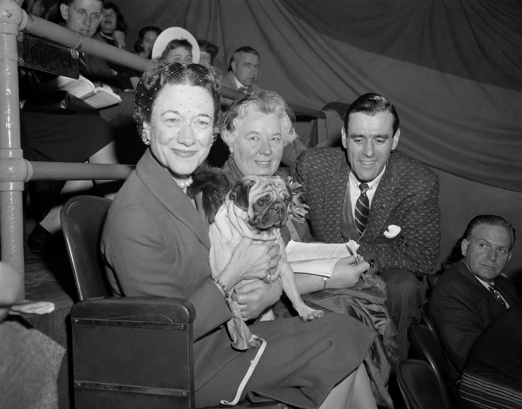 FILE - The Duchess of Windsor, Wallis Simpson, left, holds Ch. Pugville's Golden Victory during judging of the pug class during the Westminster Kennel Club Show at Madison Square Garden in New York, Feb. 13, 1956, as the dog's owner, Arnold Canton, far right, and dog breeder Harriet Smith, look on. (AP Photo/Jacob Harris, File)