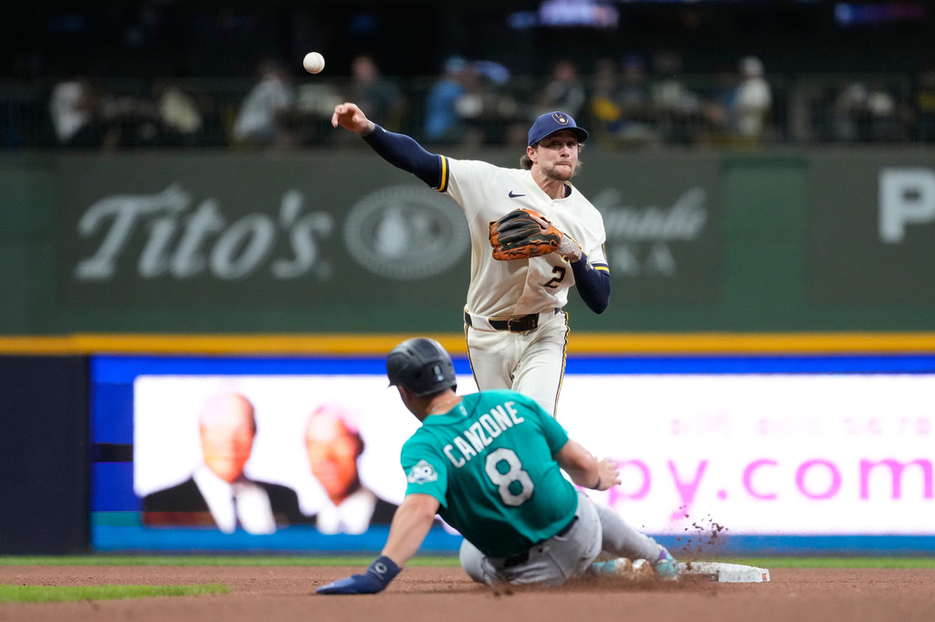 Milwaukee Brewers' Brice Turang (2) throws to first base after tagging Seattle Mariners' Dominic Canzone (8) out at second during the fourth inning of a baseball game Wednesday, Aug. 19, 2026, in Milwaukee. (AP Photo/Aaron Gash)