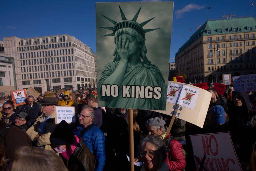 A woman displays a "No Kings" sign as she participates in a pro-democracy, anti-Trump protest outside the US embassy at the Pariser Platz square in Berlin, Saturday, Oct. 18, 2025. (AP Photo/Markus Schreiber)