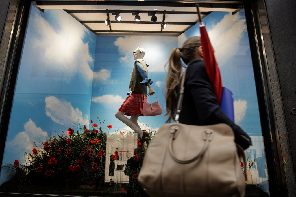 FILE - A woman walks past the Gucci store window at the Via Montenapoleone fashion district during Milan's fashion week in Milan, Italy, Sept. 25, 2020. (AP Photo/Luca Bruno, File)
