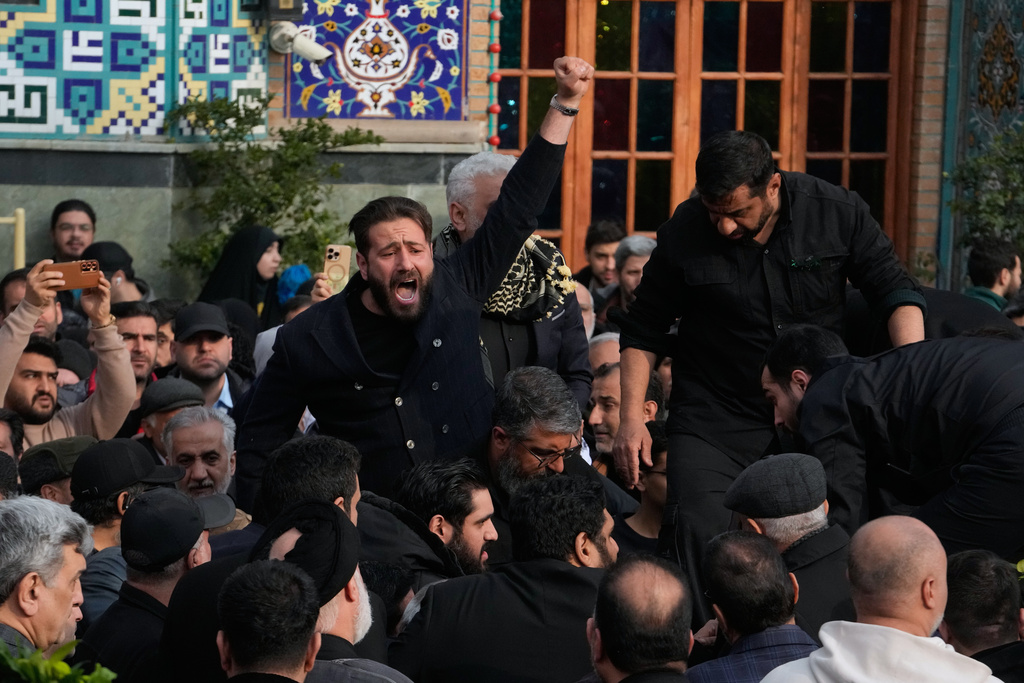 A man chants slogan while the body of Gen. Ali Shamkhani, secretary of Iran's Defense Council and a senior adviser to the Supreme Leader who was killed in a strike, is being buried at the courtyard of the Imamzadeh Saleh shrine in Tehran, Iran, Saturday, March 14, 2026. (AP Photo/Vahid Salemi)