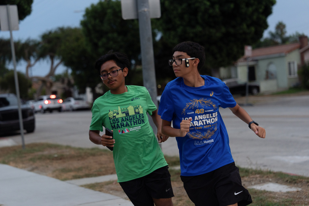 Joshua Perez, right, and Jayden Chamale, members of the Huntington Park Run Club, run through a neighborhood in Huntington Park, Calif., Sept. 17, 2025. (AP Photo/Jae C. Hong)