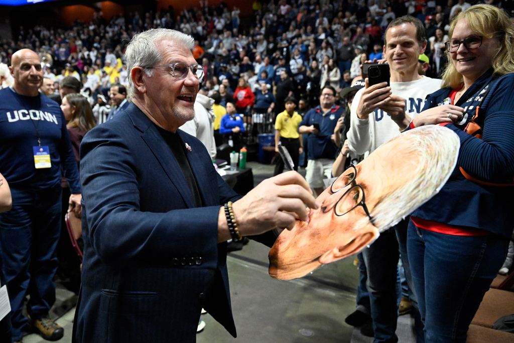 UConn head coach Geno Auriemma signs a large head of himself after his team won an NCAA college basketball game against Villanova in the finals of the Big East tournament, Monday, March 9, 2026, in Uncasville, Conn. (AP Photo/Jessica Hill)
