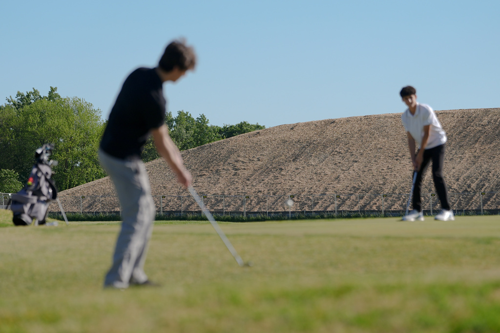 A pile of debris is seen in the background as Roman Sandoli, right, prepares to putt at the East Potomac Golf Course, Sunday, May 3, 2026, in Washington. (AP Photo/Julia Demaree Nikhinson)