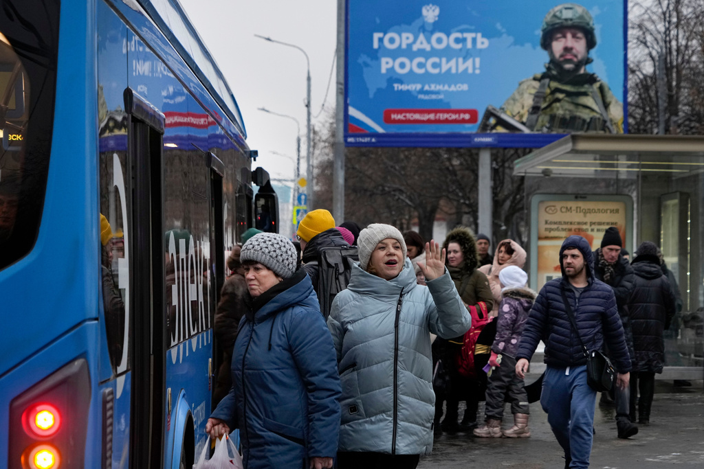 FILE - People wait at a bus stop with an advertisement showing a soldier with the slogan, "Pride of Russia," in Moscow, Russia, Feb. 11, 2025. (AP Photo/Alexander Zemlianichenko, File)