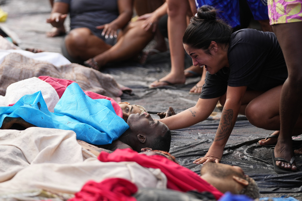 EDS NOTE: GRAPHIC CONTENT - A woman mourns beside the bodies of people killed the day before during a police raid targeting the Comando Vermelho gang in the Complexo da Penha favela of Rio de Janeiro, Brazil, Wednesday, Oct. 29, 2025. (AP Photo/Silvia Izquierdo)