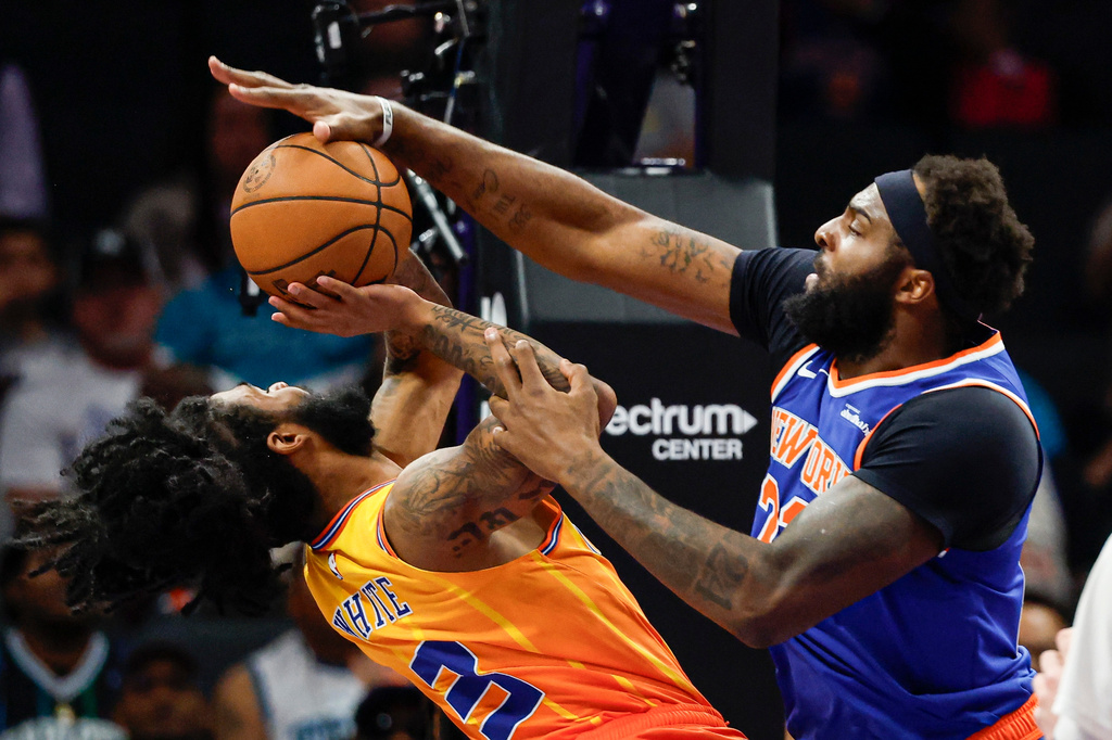 New York Knicks center Mitchell Robinson, right, blocks a shot by Charlotte Hornets guard Coby White during the first half of an NBA basketball game in Charlotte, N.C., Thursday, March 26, 2026. (AP Photo/Nell Redmond)