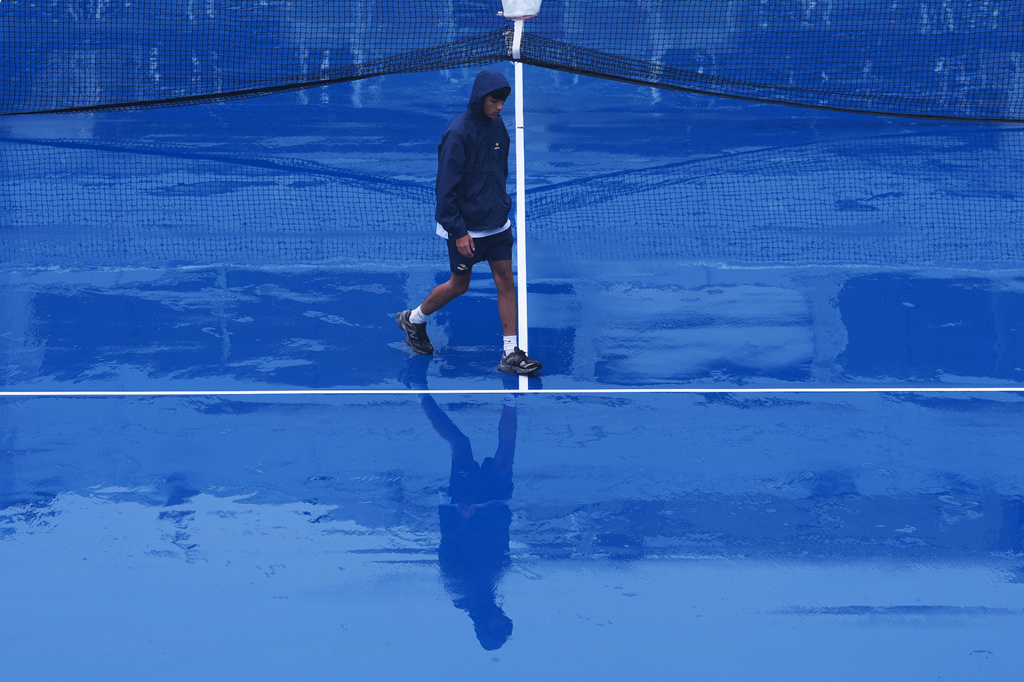 A crew member walks across the court at Grandstand stadium during a rain delay at the U.S. Open tennis championships Tuesday, Sept. 1, 2026, in New York. (AP Photo/Kirsty Wigglesworth)