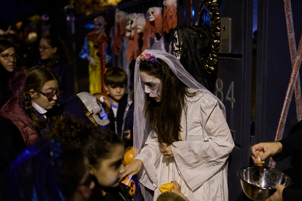 People dressed in scary costumes take part in a Halloween celebration that gives sweets to children in Paracuellos del Jarama, Spain, Friday, Oct. 31, 2025. (AP Photo/Manu Fernandez)