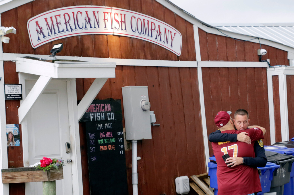 FILE - A man hugs a police officer in front of the American Fish Company following a fatal shooting that occurred the night before, Sept. 28, 2025, in Southport, N.C. (AP Photo/Chris Seward, File)