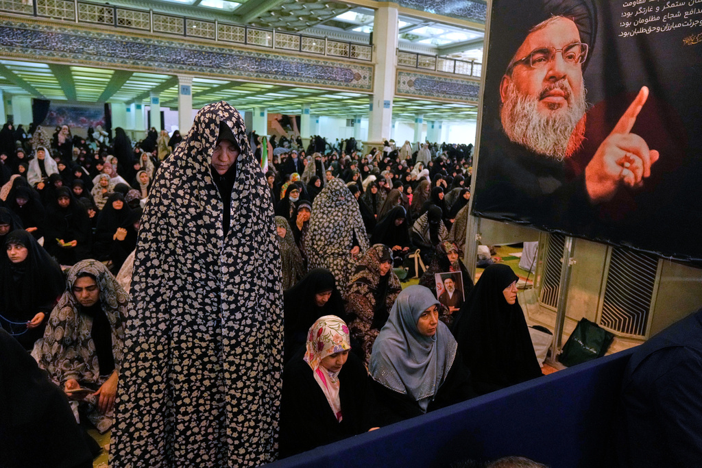 An Iranian worshipper prays during a ceremony to perform Eid al-Fitr prayers marking the end of the holy fasting month of Ramadan as a portrait of the Lebanon's slain Hezbollah leader Hassan Nasrallah is seen at right, at the Imam Khomeini Grand Mosque in Tehran, Iran, Saturday, March 21, 2026. (AP Photo/Vahid Salemi)