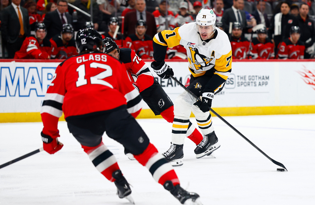 Pittsburgh Penguins center Evgeni Malkin (71) shoots against New Jersey Devils centers Cody Glass (12) and Nick Bjugstad (72) during the first period of an NHL hockey game, Thursday, April 9, 2026, in Newark, N.J. (AP Photo/Noah K. Murray)