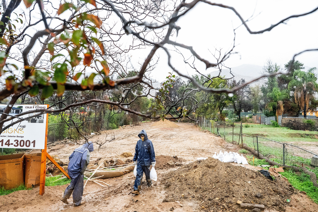 James Jones carries sandbags while trying to prevent water from running off a property scorched in the Eaton Fire in Altadena, Calif., as the region remains under flash flood warnings on Saturday, Nov. 15, 2025. (AP Photo/Noah Berger)