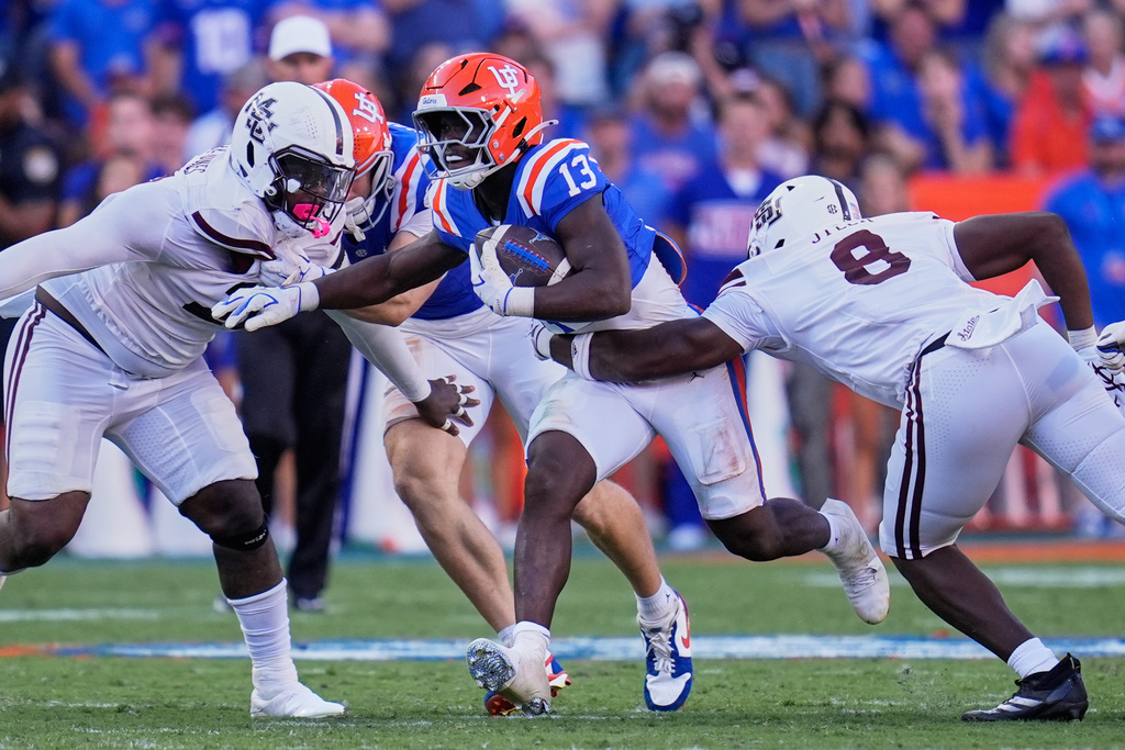 Florida running back Jadan Baugh (13) runs between Mississippi State cornerback Jett Jefferson, left, and linebacker Malick Sylla (8) during the first half of an NCAA college football game, Thursday, Sept. 18, 2025, in Gainesville, Fla. (AP Photo/John Raoux)