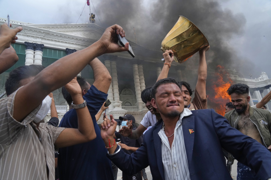 Protesters celebrate at the Singha Durbar, the seat of Nepal's government's various ministries and offices after burning it down during a protest against social media ban and corruption in Kathmandu, Nepal, Tuesday, Sept. 9, 2025. (AP Photo/Niranjan Shrestha)