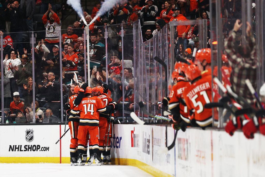 Anaheim Ducks players embrace Anaheim Ducks center Leo Carlsson (91) after scoring during the second period of an NHL hockey game Thursday, Oct. 16, 2025, in Anaheim, Calif. (AP Photo/Ethan Swope)
