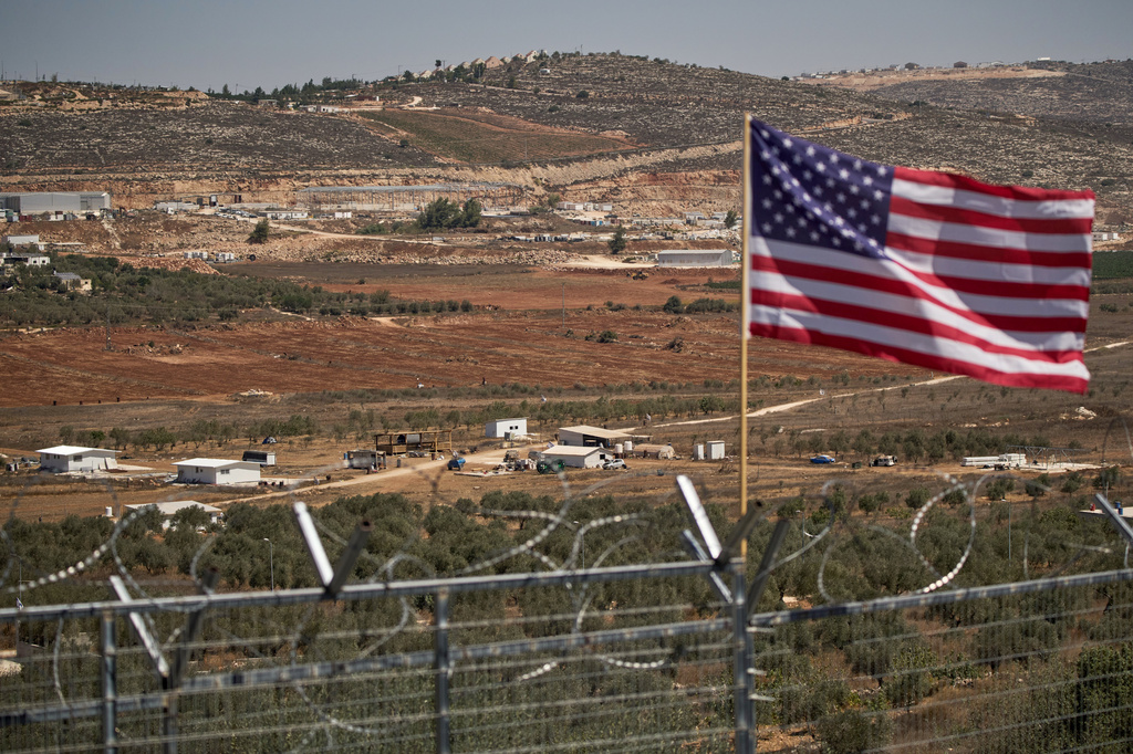 FILE - A U.S. flag waves at the entrance of a Palestinian house as an Israeli settler outpost stands in the middle of a valley next to olive trees in the West Bank town of Turmus Ayya, Sept. 9, 2026. (AP Photo/Leo Correa, File)