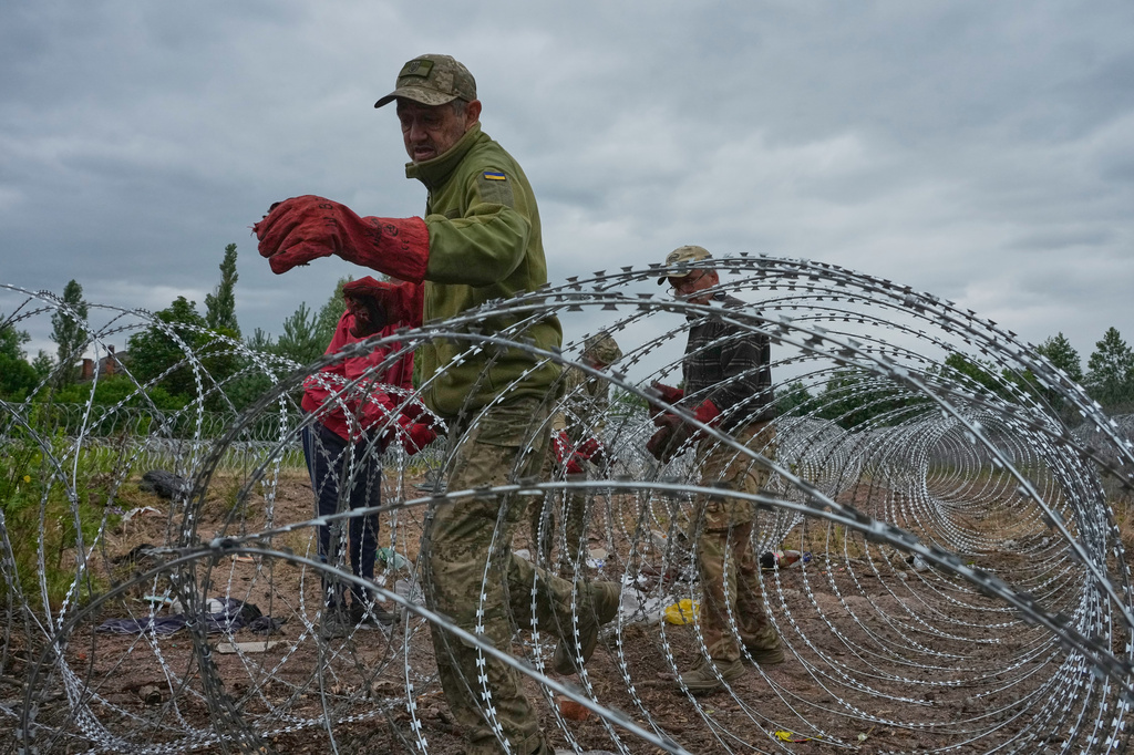 Ukrainian workers install barbed wire close to the Ukraine-Belarus border in an undisclosed location in Ukraine Tuesday, July 7, 2026. (AP Photo/Efrem Lukatsky)