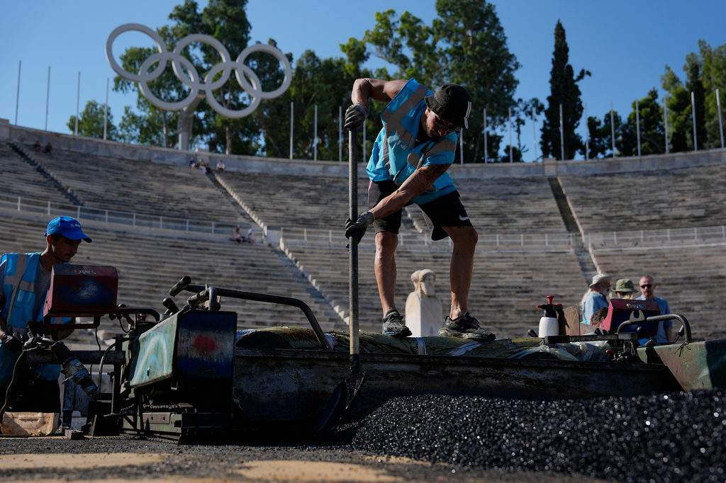 Workers lay asphalt at the Panathenaic Stadium, also known as "Kallimarmaro, or beautiful marble," which hosted the first modern Olympic Games in 1896, during renovation work in Athens, Greece, Thursday, Aug. 13, 2026. (AP Photo/Thanassis Stavrakis)