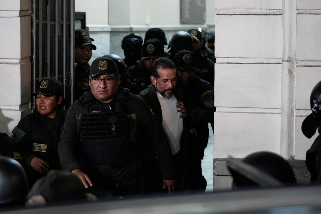 Suspended governor of Santa Cruz Luis Fernando Camacho is escorted by police out of court after a hearing on his arrest over charges of sedition and terrorism, in La Paz, Bolivia, Tuesday, Aug. 26, 2025. (AP Photo/Juan Karita)