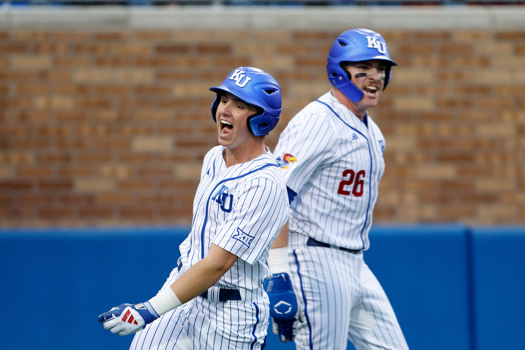 FILE - Kansas' Tyson LeBlanc, left, and Brady Ballinger (26) react after scoring off a Dariel Osoria single during eighth inning of an NCAA college baseball game against St. Thomas on March 5, 2026, in Lawrence, Kan. (AP Photo/Colin E. Braley, file)