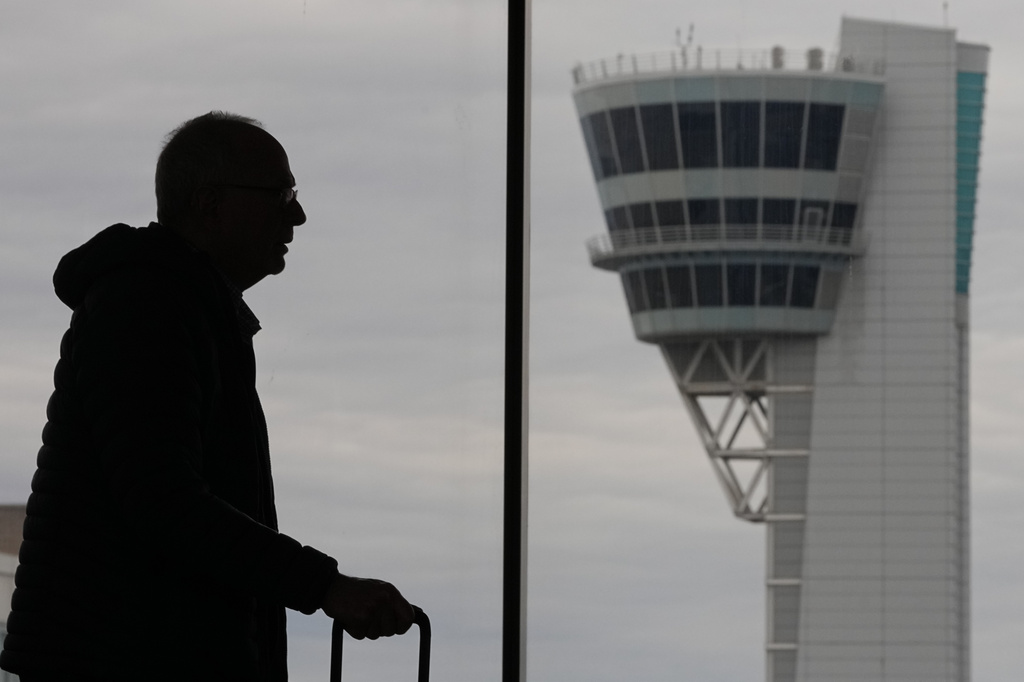 A traveler moves in view of an air traffic control tower at Philadelphia International Airport in Philadelphia, Friday, March 27, 2026. (AP Photo/Matt Rourke)