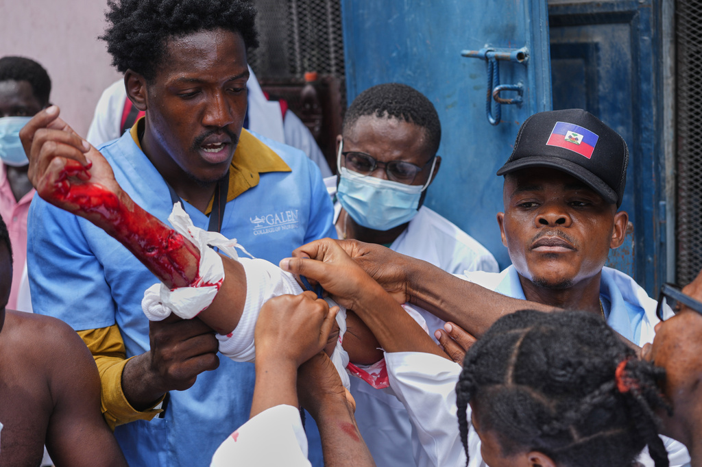Medical students help a fellow student shot by a uniformed policeman who fired trying to disperse the crowd during a protest march demanding the reopening of the General Hospital, in Port-au-Prince, Haiti, Wednesday, July 1, 2026. (AP Photo/Odelyn Joseph)