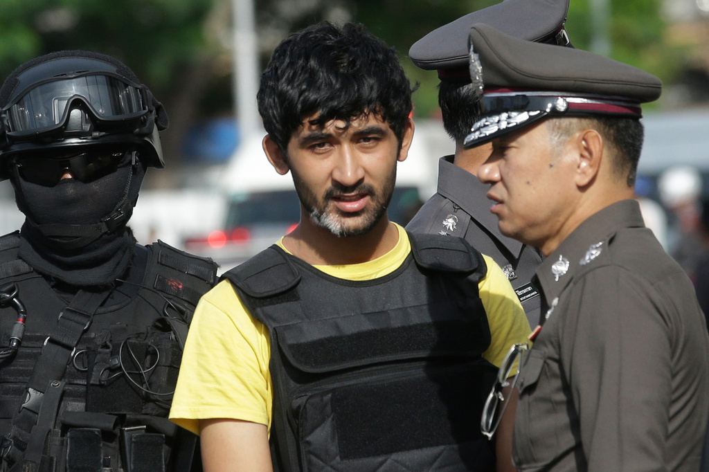 FILE - Police officers escort Yusufu Mieraili, yellow shirt, outside Hua Lamphong railway station in Bangkok, on Sept. 9, 2015. (AP Photo/Sakchai Lalit, File)