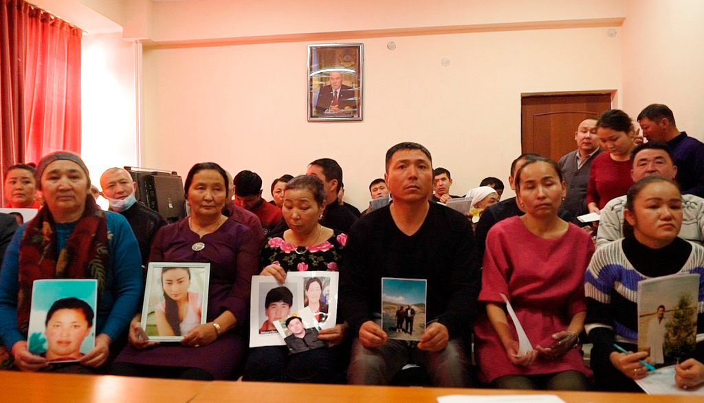 FILE - In this image made from video, relatives of people missing in China's far western region of Xinjiang hold up photos at an office of a Chinese Kazakh advocacy organization in Almaty, Kazakhstan, Dec. 7, 2018. (AP Photo/Dake Kang, File)