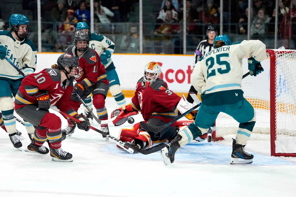 Seattle Torrent's Alex Carpenter (25) tries to get a piece of the puck as it bounces behind Ottawa Charge goaltender Gwyneth Philips (33) during second period PWHL hockey action in Ottawa, on Wednesday, Jan. 28, 2026. (Justin Tang/The Canadian Press via AP)