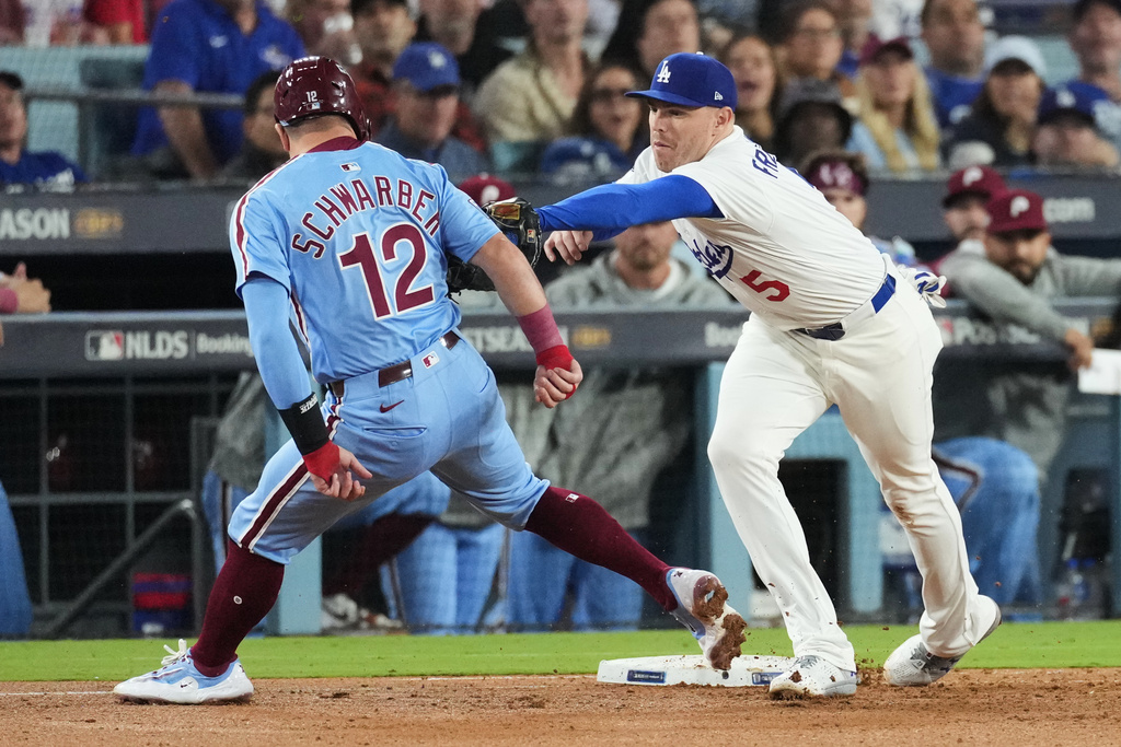 Philadelphia Phillies' Kyle Schwarber, left, is tagged out by Los Angeles Dodgers first baseman Freddie Freeman on a pickoff throw from catcher Will Smith during the seventh inning in Game 3 of baseball's National League Division Series Wednesday, Oct. 8, 2025, in Los Angeles. (AP Photo/Jae C. Hong)