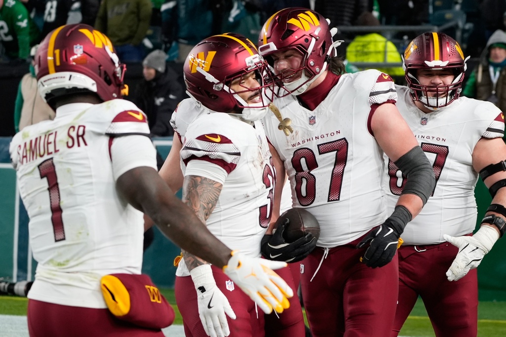 Washington Commanders tight end John Bates (87) celebrates scoring a touchdown with teammates during the second half of an NFL football game against the Philadelphia Eagles on Sunday, Jan. 4, 2026, in Philadelphia. (AP Photo/Chris Szagola)