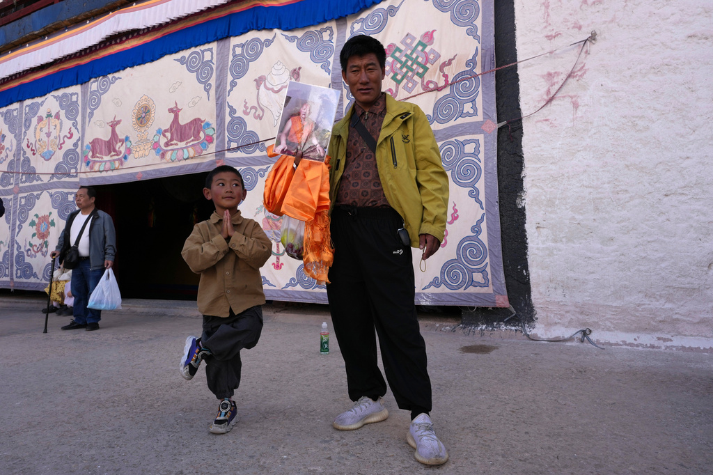A child reacts to a man holding a photo of a Tibetan monk during a visit to the Potala Palace in Lhasa in western China's Tibet Autonomous Region on Tuesday, July 21, 2026, as seen during a government organized visit for foreign journalists. (AP Photo/Ng Han Guan)